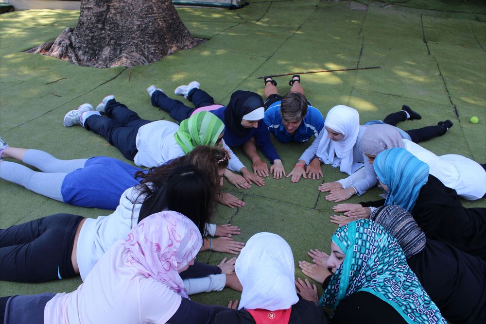 Members lying in a circle on the grass at camp