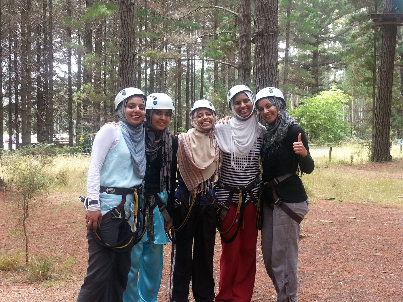 Members in helmets and harnesses at a high ropes course