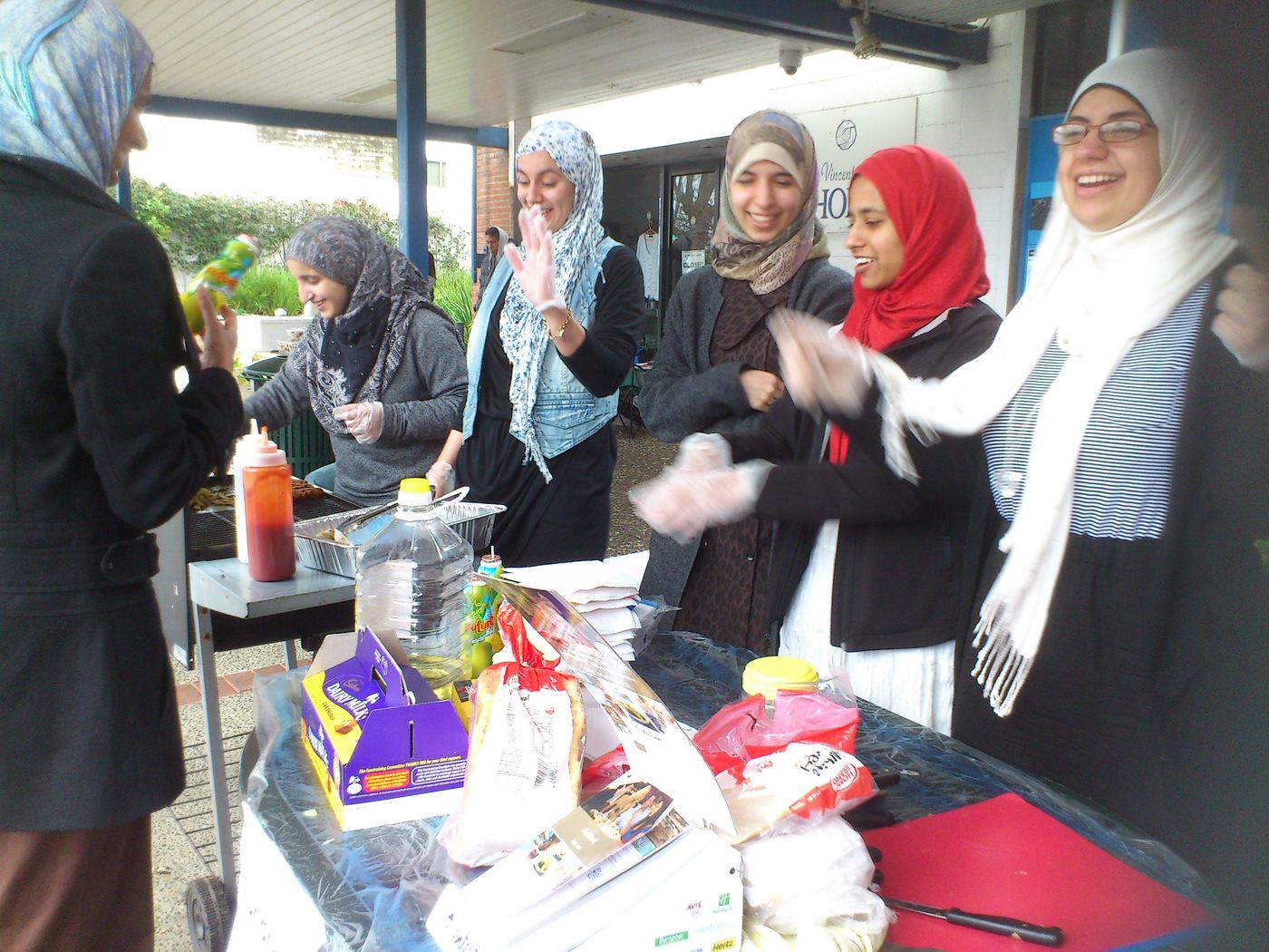 YMWA members laughing together at a fundraiser stall